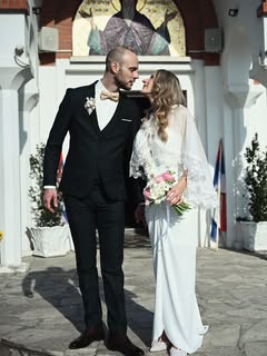 Mladenci ispred crkve sa buketom